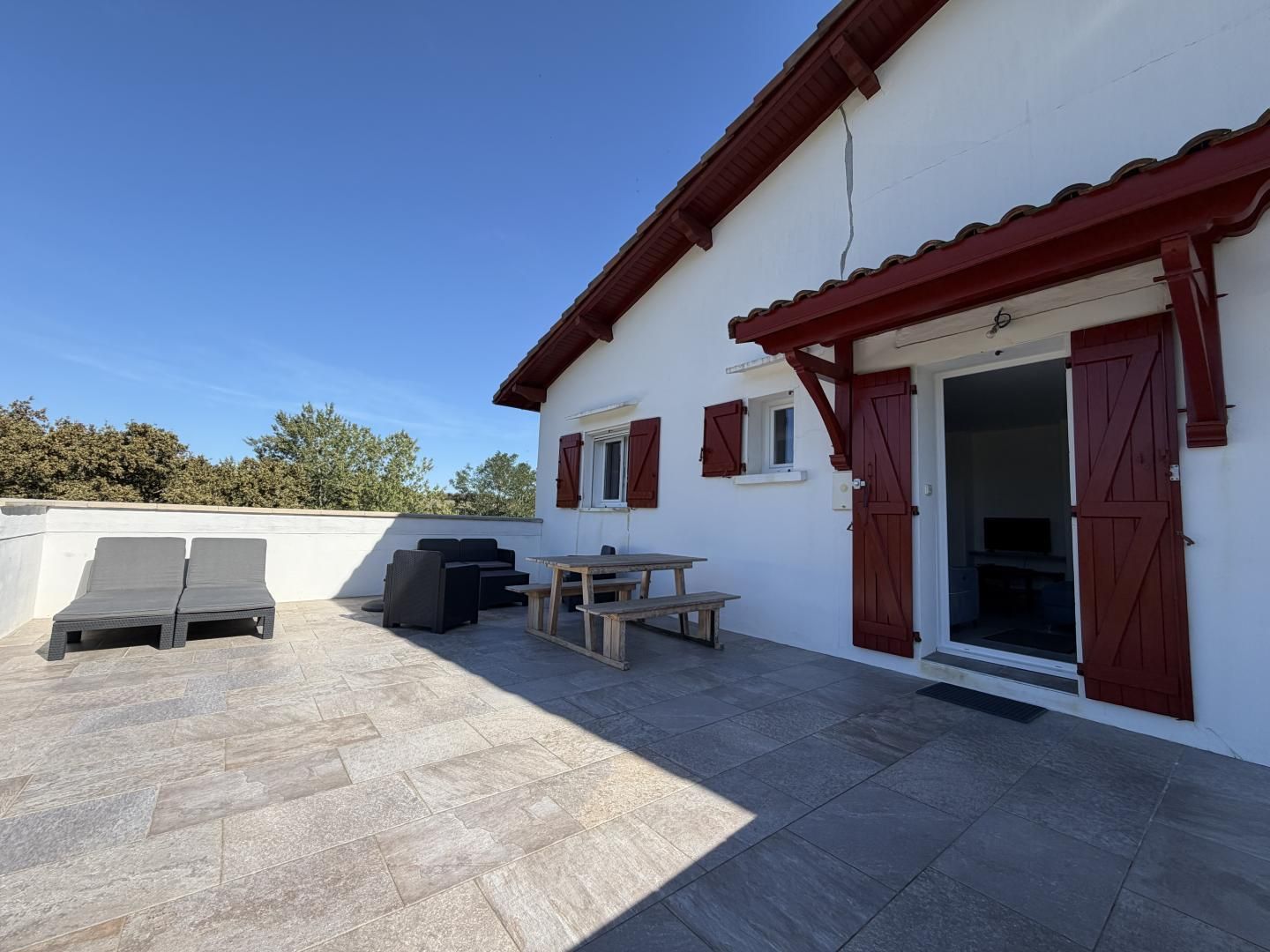 Een terras met een tafel, stoelen, een bank en een schuifdeur.