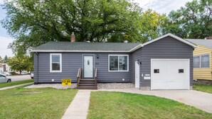 A two-story house with a front door, a garage, and a small front yard. - Stylish Home a Block Away from Entertainment (Fargo)