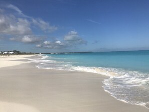 A beach with clear turquoise water, a sandy shore, and a few buildings in the distance. - Ocean Harmony – your luxurious, peaceful retreat by the Beach (Treasure Cay)