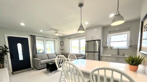 Une cuisine moderne avec des meubles blancs, un îlot central et des luminaires suspendus.
