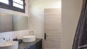 A modern bathroom with two round white sinks, a large mirror, and a wooden door. - Romantic Villa Laupie 5 minutes from Case Pilote, a haven of peace (CASE PILOTE)