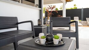 A patio with two black chairs, a small table with a tray holding a black pot and three small potted plants. - Romantic Villa Laupie 5 minutes from Case Pilote, a haven of peace (CASE PILOTE)