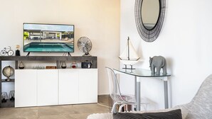 A modern living room with a TV, a glass table, and a decorative mirror. - Romantic Villa Laupie 5 minutes from Case Pilote, a haven of peace (CASE PILOTE)