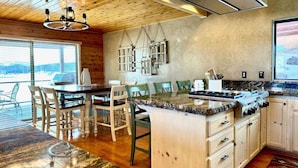 A modern kitchen with wooden cabinets, a granite countertop, and a dining area with chairs.