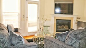 A living room with a fireplace, a television above it, and a door leading outside. - Ravishing Downtown Home (Atlanta)