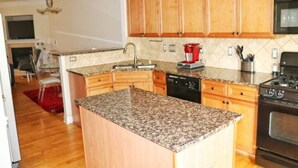A kitchen with wooden cabinets, granite countertops, a dishwasher, a stove, and a microwave. - Ravishing Downtown Home (Atlanta)