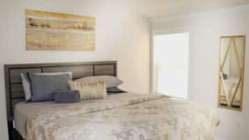 A bedroom with a bed, a painting on the wall, and a mirror.