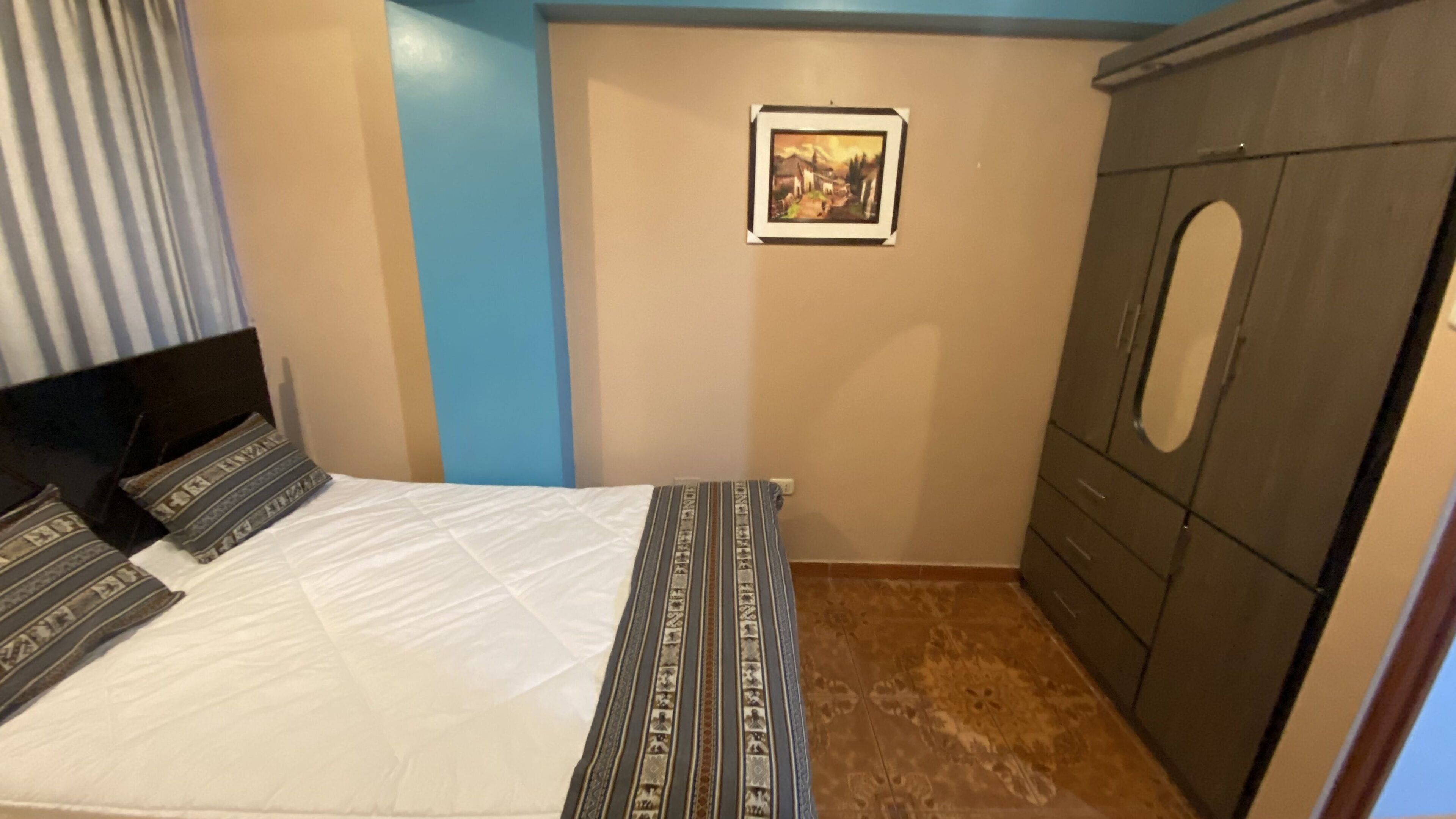 Une chambre à coucher avec un lit, une armoire et un tableau encadré au mur.