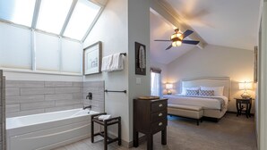 Un dormitorio moderno con una cama grande, una mesita de noche, un aparador y un ventilador de techo.