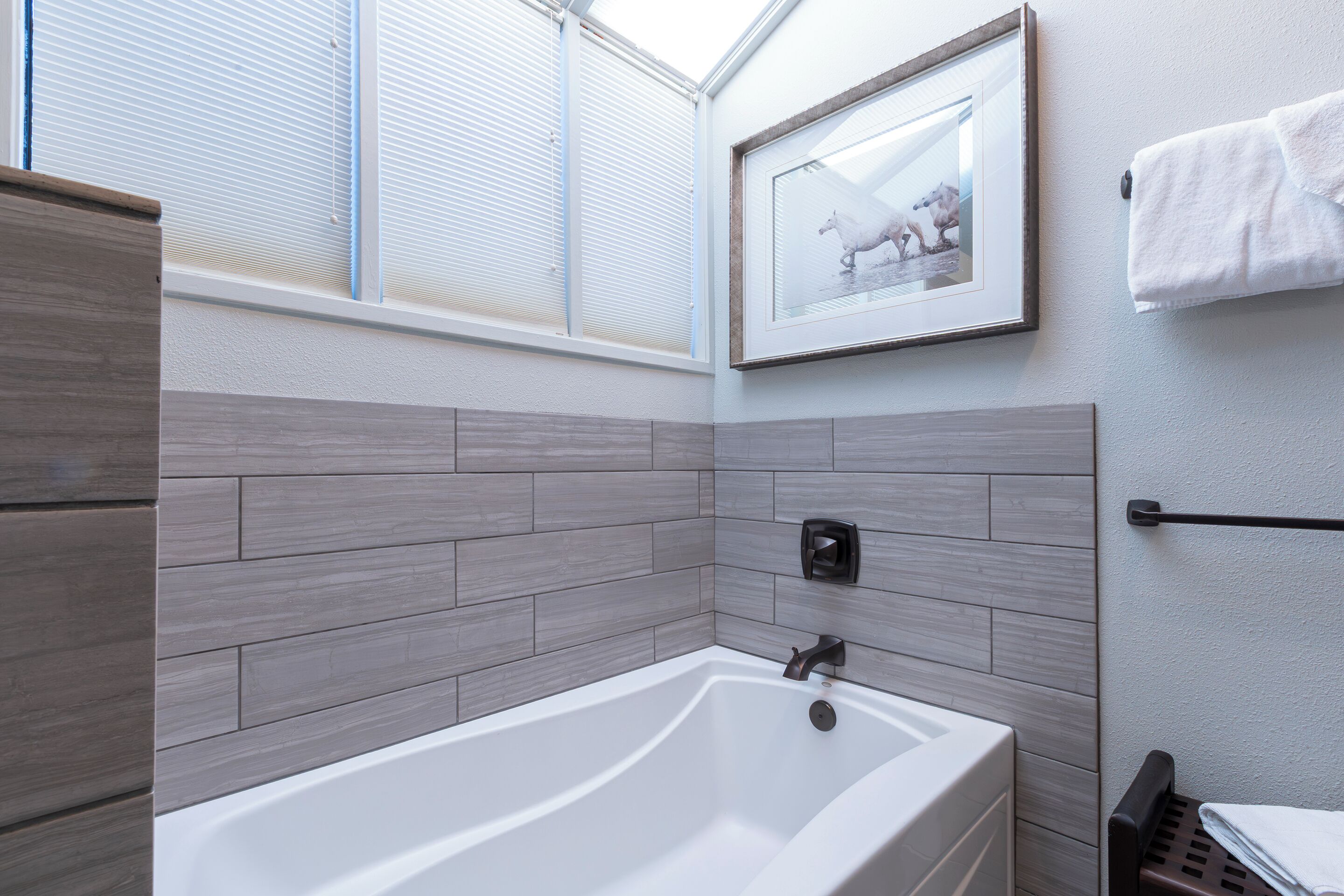 Une salle de bain moderne avec une baignoire sur pieds, un tableau encadré au mur et un porte-serviettes.
