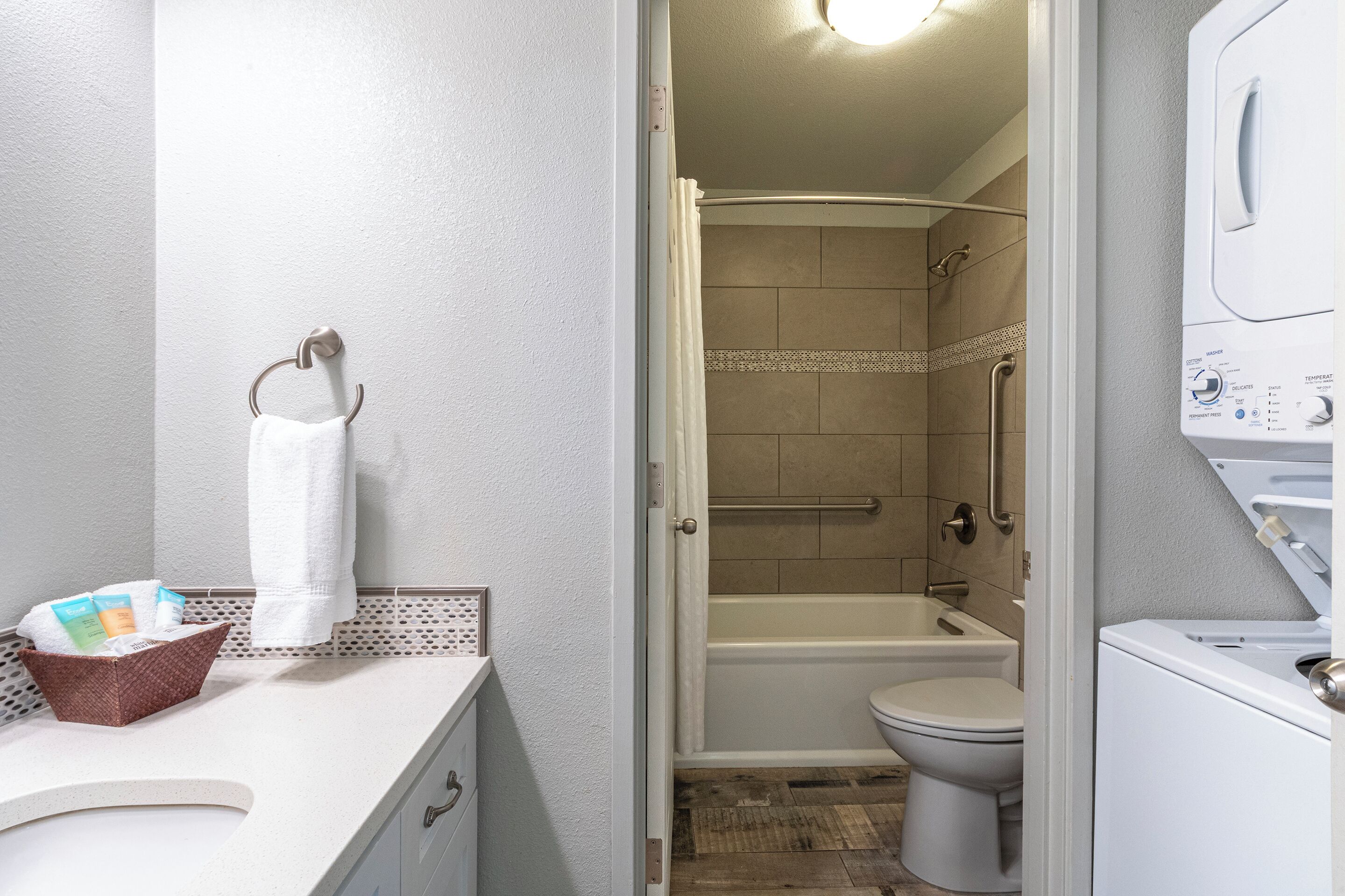 Une salle de bain avec des toilettes, une douche et un lave-linge blanc.