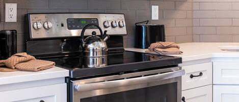 A modern kitchen with stainless steel appliances, a kettle, and a stove.