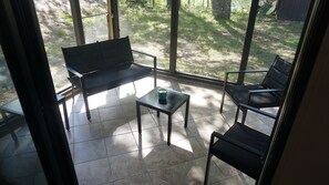 Um pátio ensolarado com um banco, uma mesa e duas cadeiras.