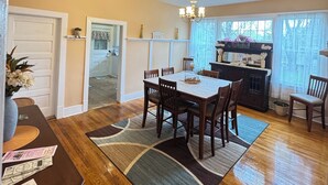 A dining area with a wooden table, chairs, a chandelier, and a patterned ceiling. - Charming Victorian at Lake Shelbyville ⋅ Sleeps 6 ⋅Sunroom ⋅ Fire Pit ⋅ Parking (Shelbyville)