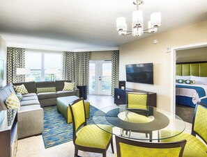Et moderne hotelværelse med en sofa, et glasbord og et fjernsyn.