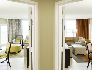 Une chambre d’hôtel moderne dotée d’un espace salon comprenant un canapé, une table basse ronde et un tapis à motifs.