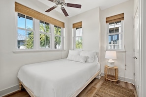 A bedroom with a bed, a ceiling fan, and a window with a view of palm trees. - Charming Carriage House, Prime Location- Walk to Rosemary and 30A (Inlet Beach)