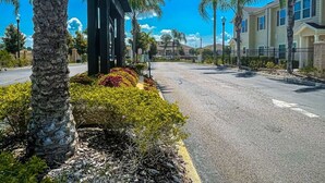 Una calle residencial con casas, palmeras y un cielo despejado.