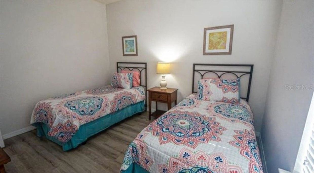 A bedroom with two single beds, a bedside table with a lamp, and a framed picture on the wall.