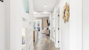Un couloir doté d’un plancher en bois, de murs blancs et d’un élément décoratif mural.