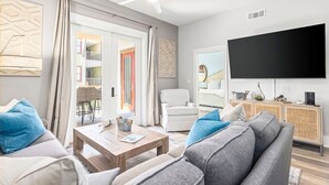 Un salon avec un canapé, une table basse et un téléviseur à écran plat.