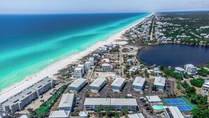 Eine Luftaufnahme eines Küstenresorts mit Strandhäusern, einem Tennisplatz und einer großen Wasserfläche.