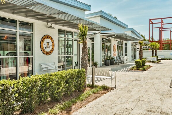 A modern building with a large glass facade, outdoor seating, and a logo on the wall.