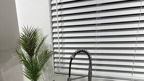 Una cocina con un lavamanos doble, una planta en maceta y una ventana con persianas.