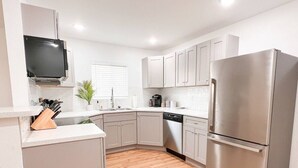 Una cocina moderna con refrigerador de acero inoxidable, gabinetes blancos, lavavajillas y horno empotrado.