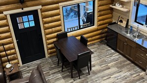 Ein Holzblockhaus-Interieur mit Essbereich, Küche und Sitzgelegenheiten.