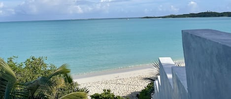 A beach with clear turquoise water, a sandy shore, and a distant island.