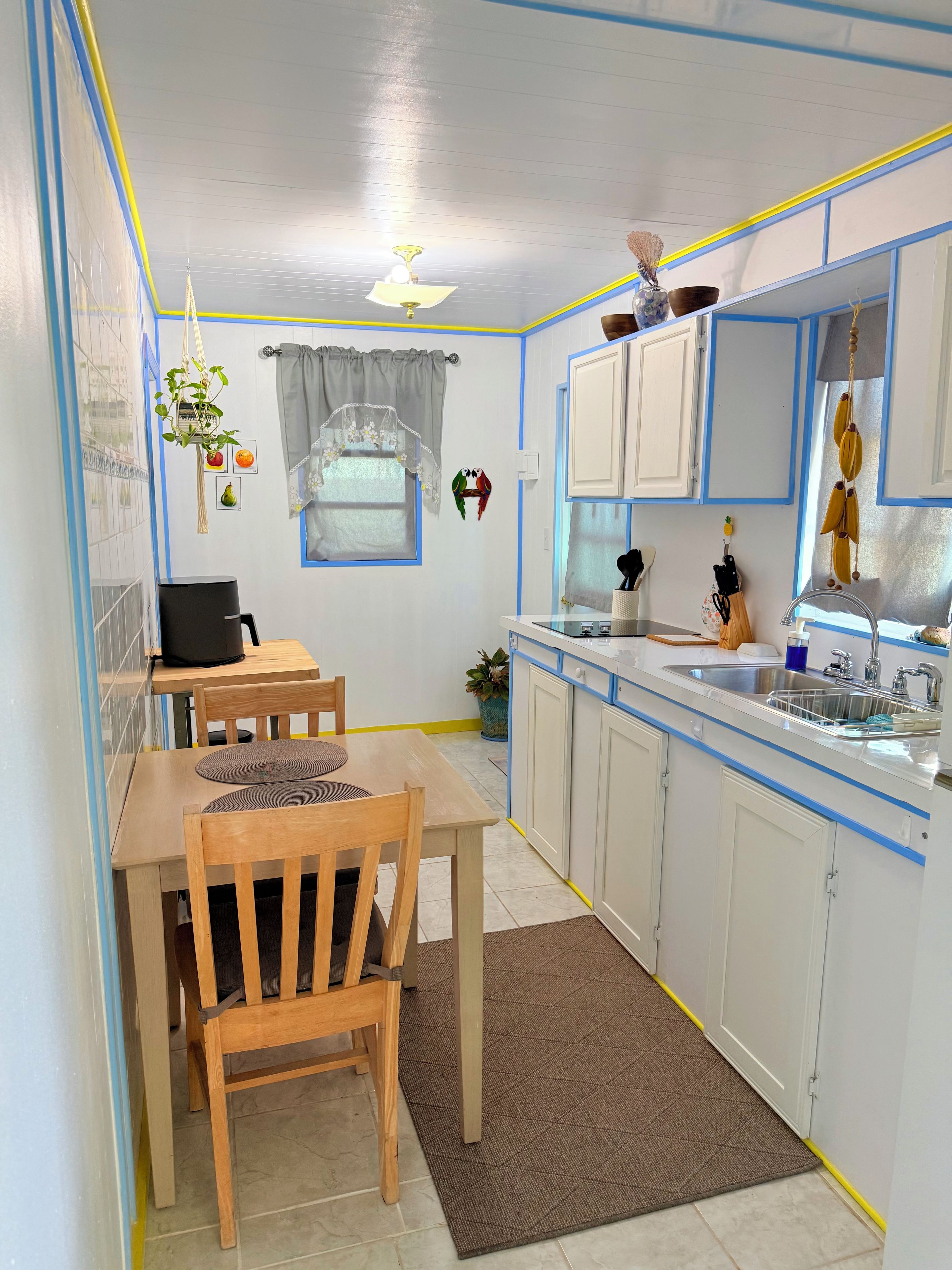 A compact kitchen with a dining area, featuring cabinets, a sink, and a ceiling fan.