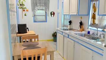 A compact kitchen with a dining area, featuring cabinets, a sink, and a ceiling fan.