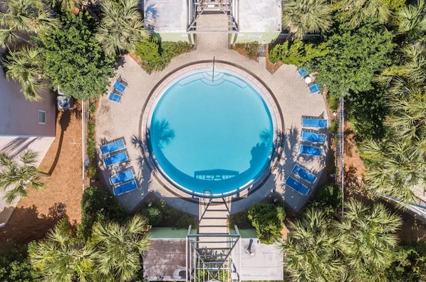 An aerial view of a circular swimming pool surrounded by palm trees and lounge chairs. - Walking Distance To Beach! Beach Pointe Townhomes 403 (Destin)