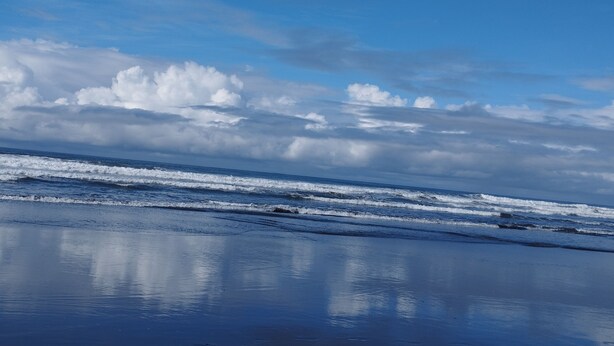 Une plage avec des vagues et un ciel nuageux.