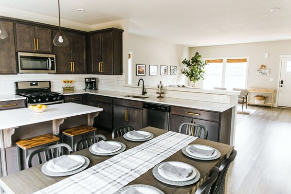 A modern kitchen with dark wood cabinets, stainless steel appliances, and a central island with seating.
