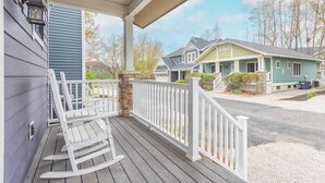 A porch with a rocking chair, a covered area with a railing, and a view of neighboring houses. - Blueberry Beach House indoor pool, hot tub (South Haven)