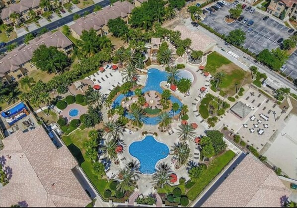 An aerial view of a resort with multiple swimming pools, palm trees, and a parking lot. - NEW RESORT STYLE TOWNHOME MINUTES AWAY FROM THEME PARKS (Davenport)