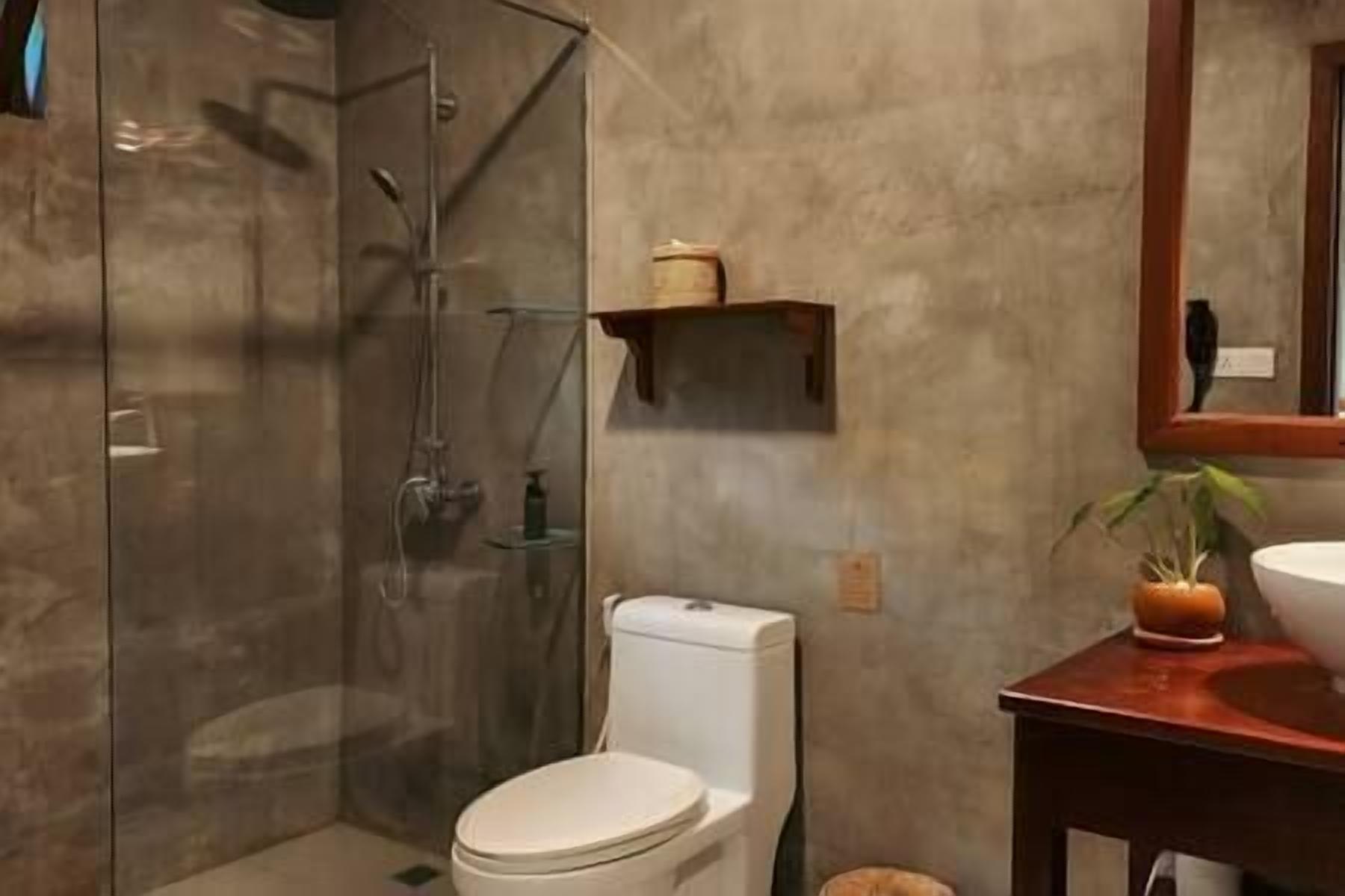 Une salle de bain avec une douche à parois de verre, des toilettes, un lavabo et un miroir.