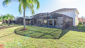Una casa moderna con un'ampia veranda vetrata, una piscina e un prato curato.