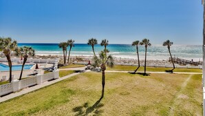 Blick auf einen Strand mit Palmen, einem Pool und blauem Himmel.