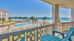 Ein Balkon mit blauen Stühlen mit Blick auf Pool und Strand.
