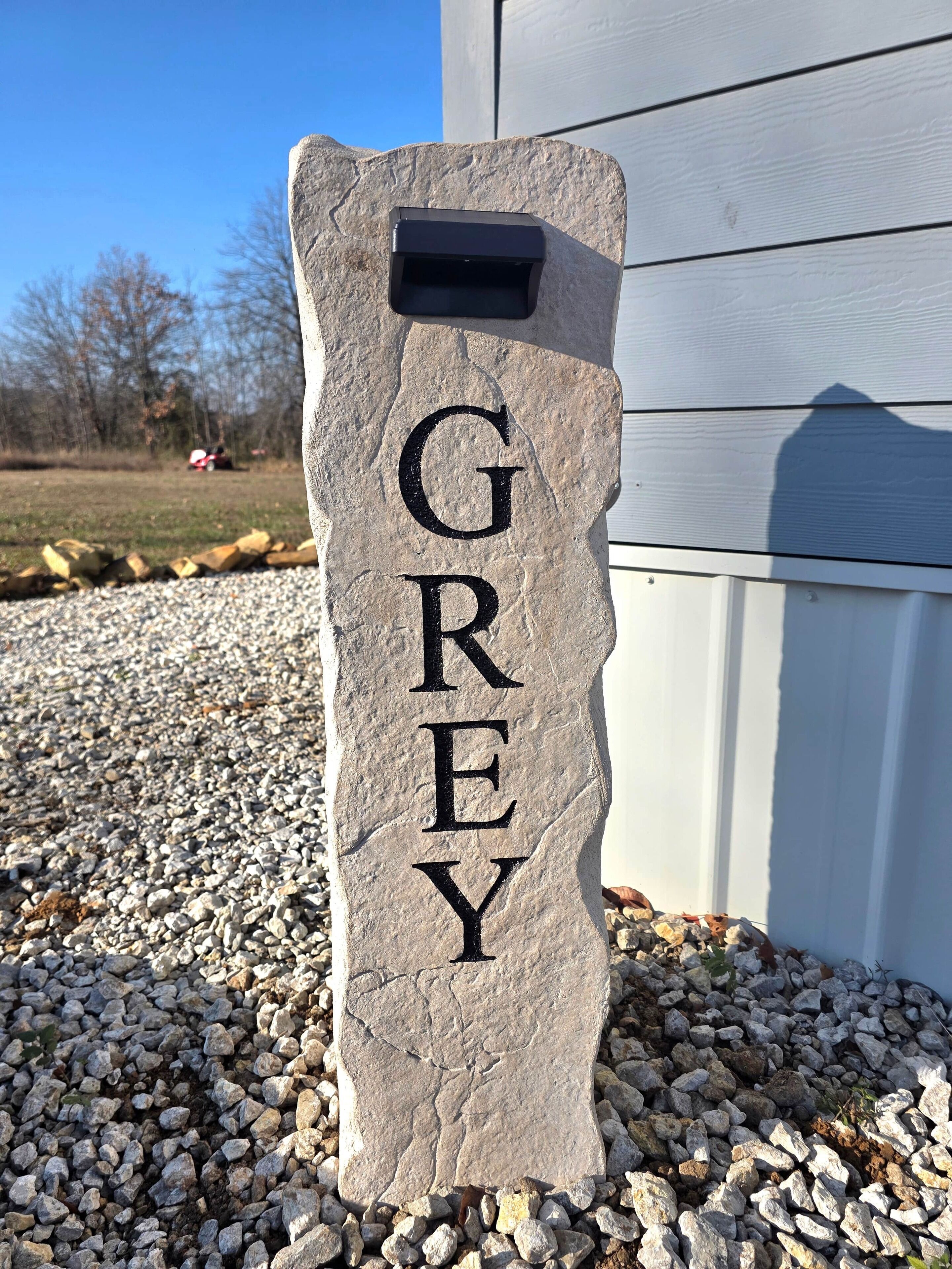 A stone sign with the name 'GREY' mounted on a post.
