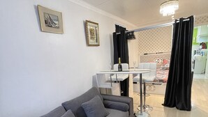 Un salon moderne avec un canapé gris, une table à manger et un lustre.
