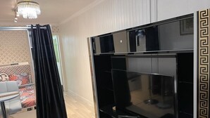 Un salon moderne avec un grand meuble de rangement noir pour les appareils multimédias, un canapé blanc et un rideau noir.