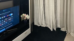 Un salon moderne avec un téléviseur à écran plat, un miroir décoratif et une plante en pot.
