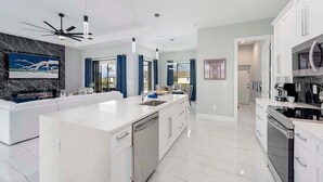 A modern kitchen with a large island, white cabinetry, and stainless steel appliances. - Paradiso - Modern Style Vacation Villa (Cape Coral)
