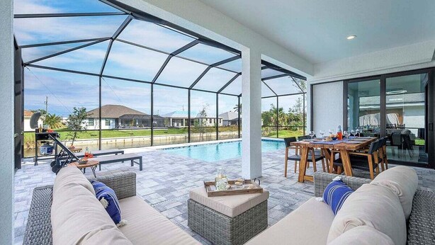 A covered outdoor area with a pool, seating, and a dining table. - Paradiso - Modern Style Vacation Villa (Cape Coral)