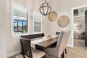 A dining area with a long table, dark wooden chairs, and a chandelier.
