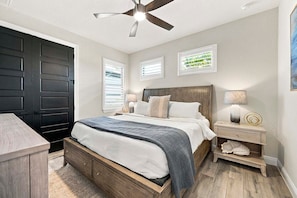 A bedroom with a bed, nightstands, a desk, a ceiling fan, and a wardrobe.